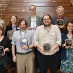 A group of Faculty and Staff stand in two rows holding their awards.
