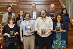 A group of Faculty and Staff stand in two rows holding their awards.