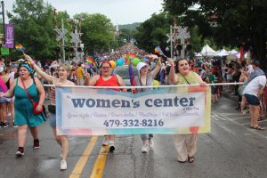 Students from the UCO womens, gender and sexuality studies program walk the Northwest Arkansas Pride Parade in holding banner for the Elder Tree Women's Center