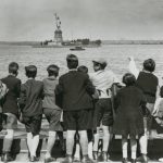 Jewish refugee children wave at the Statue of Liberty as the President Harding steams into New York harbor