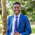 UCO MPA Student in suit smiles outside