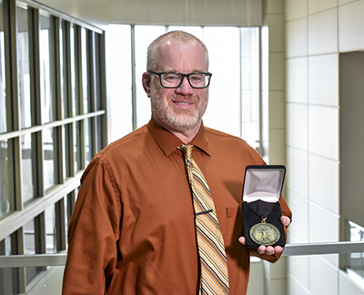 UCO professor John Wood with his award from DaVinci Institute